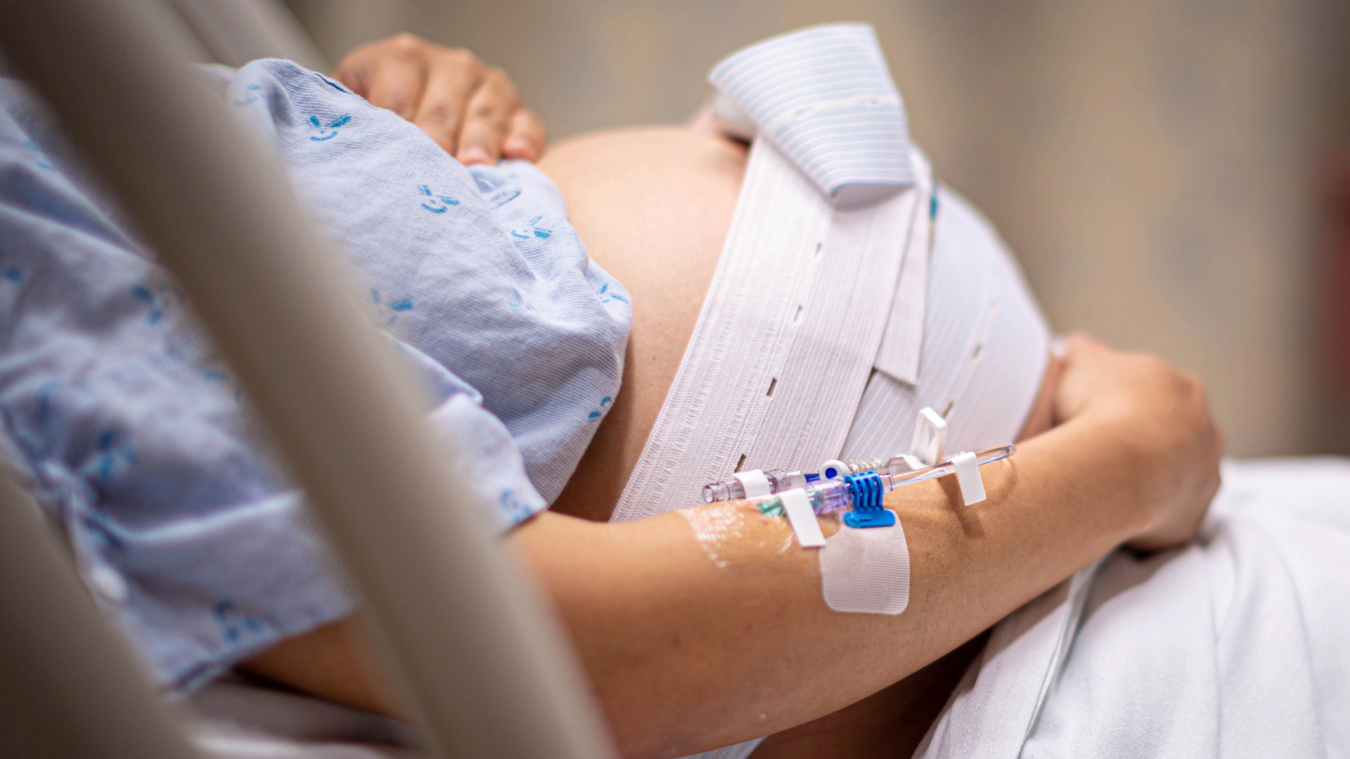 An expectant mother in a hospital bed holding her stomach.